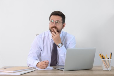 Photo of Portrait of thoughtful businessman at table against white background