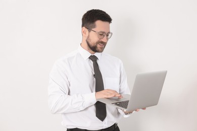 Portrait of smiling businessman working with laptop on white background