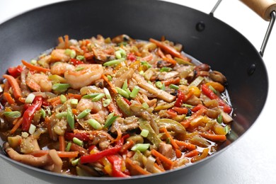 Photo of Stir-fry sea food in wok on light table, closeup