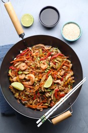 Photo of Stir-fry sea food in wok served on grey table, flat lay