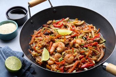 Photo of Stir-fry sea food in wok served on grey table