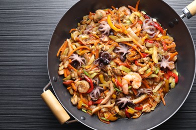 Stir-fry sea food in wok on black wooden table, top view