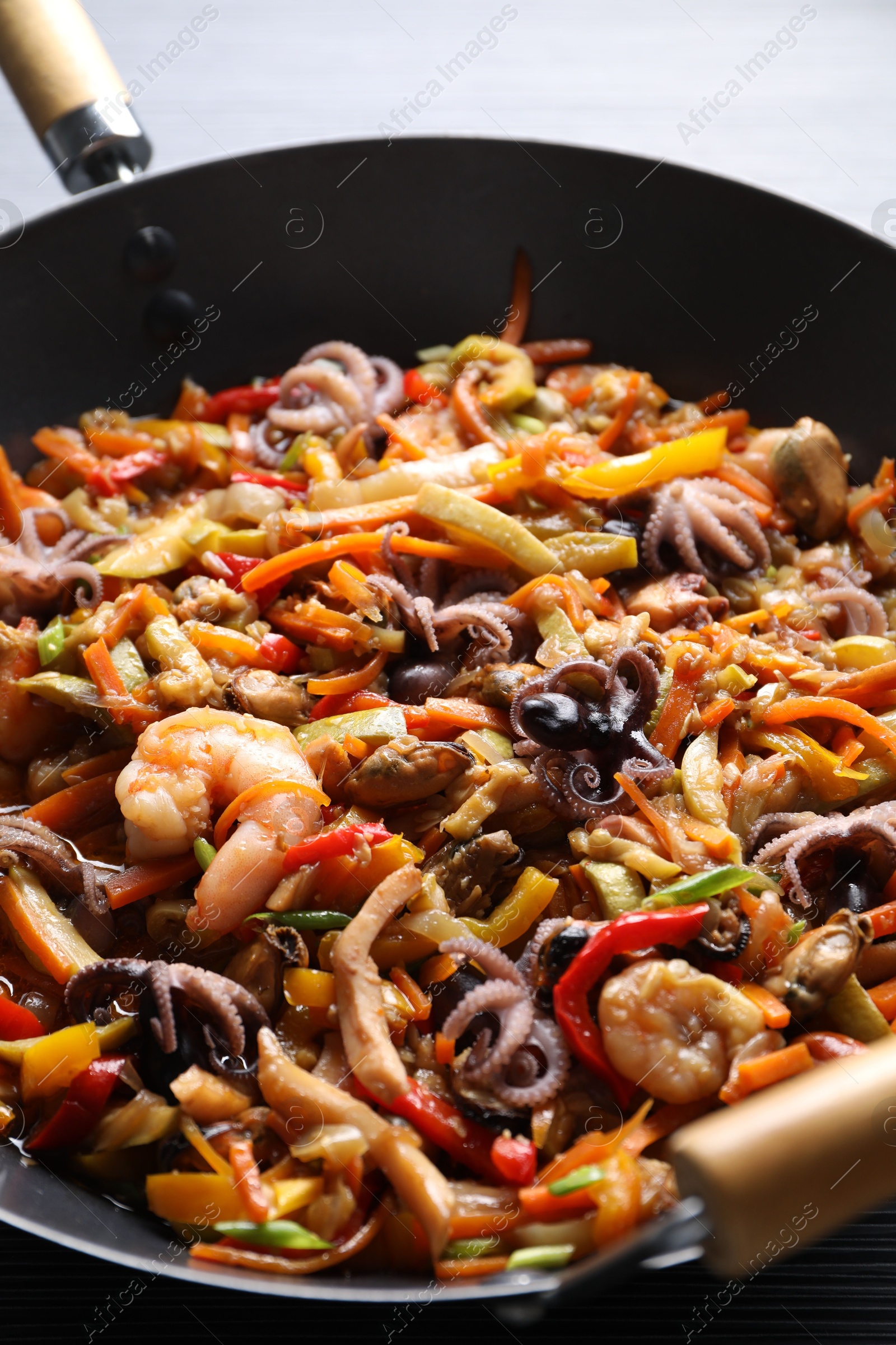 Photo of Stir-fry sea food in wok on table, closeup