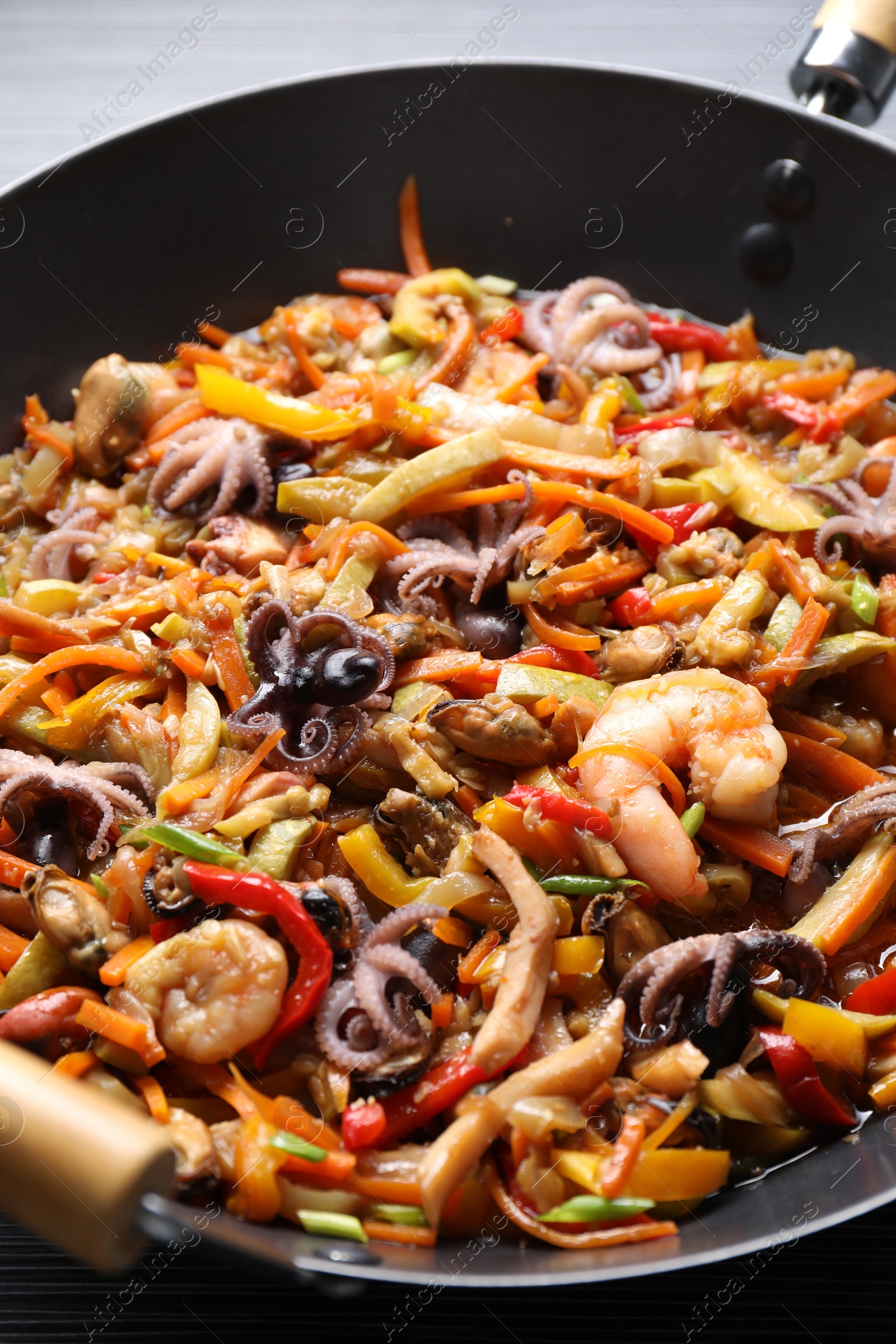 Photo of Stir-fry sea food in wok on table, closeup