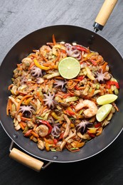 Photo of Stir-fry sea food in wok on grey textured table, top view