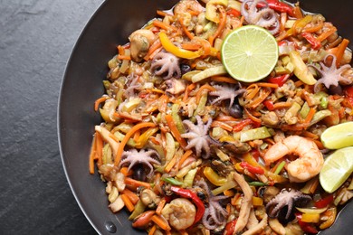 Stir-fry sea food in wok on grey textured table, top view