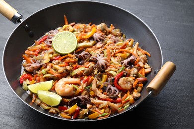 Photo of Stir-fry sea food in wok on grey textured table, closeup