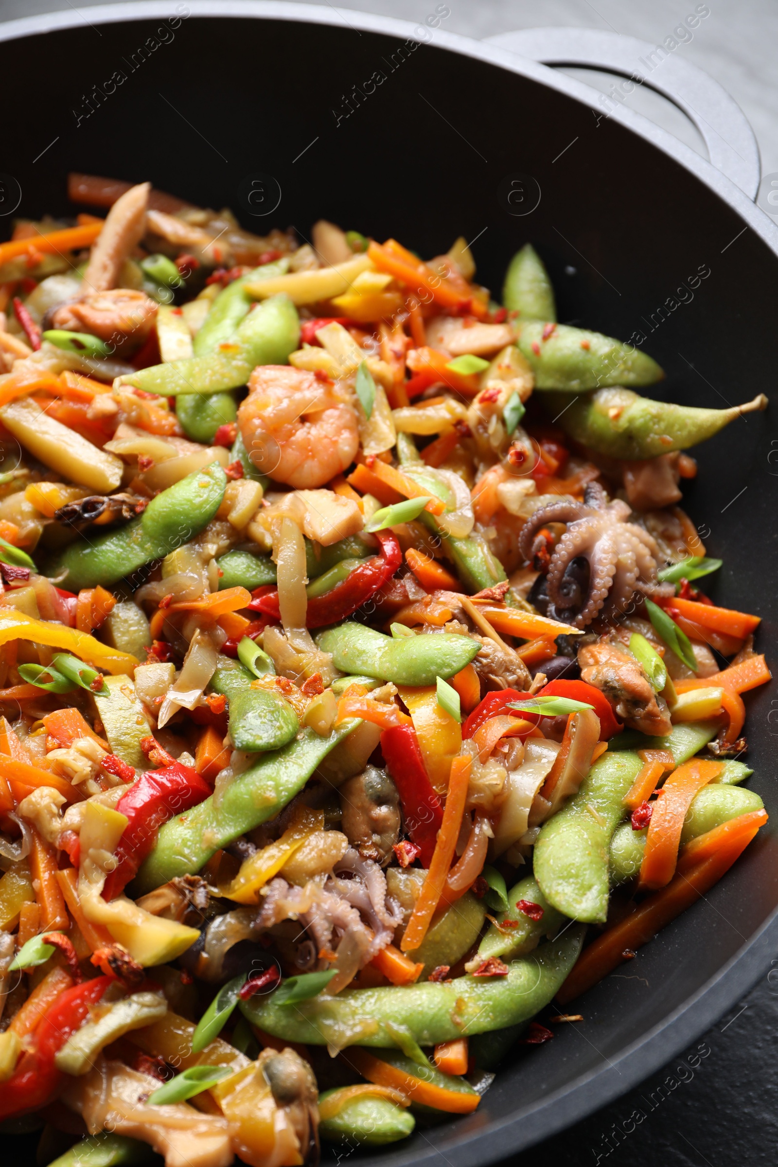 Photo of Stir-fry sea food in wok on grey table, closeup