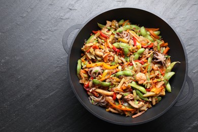 Photo of Stir-fry sea food in wok on grey textured table, top view