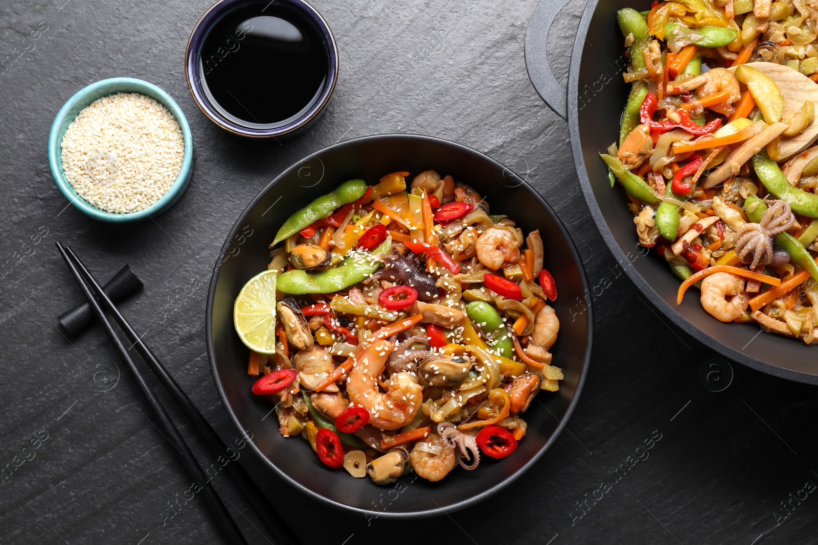 Photo of Stir-fry sea food served on grey textured table, flat lay