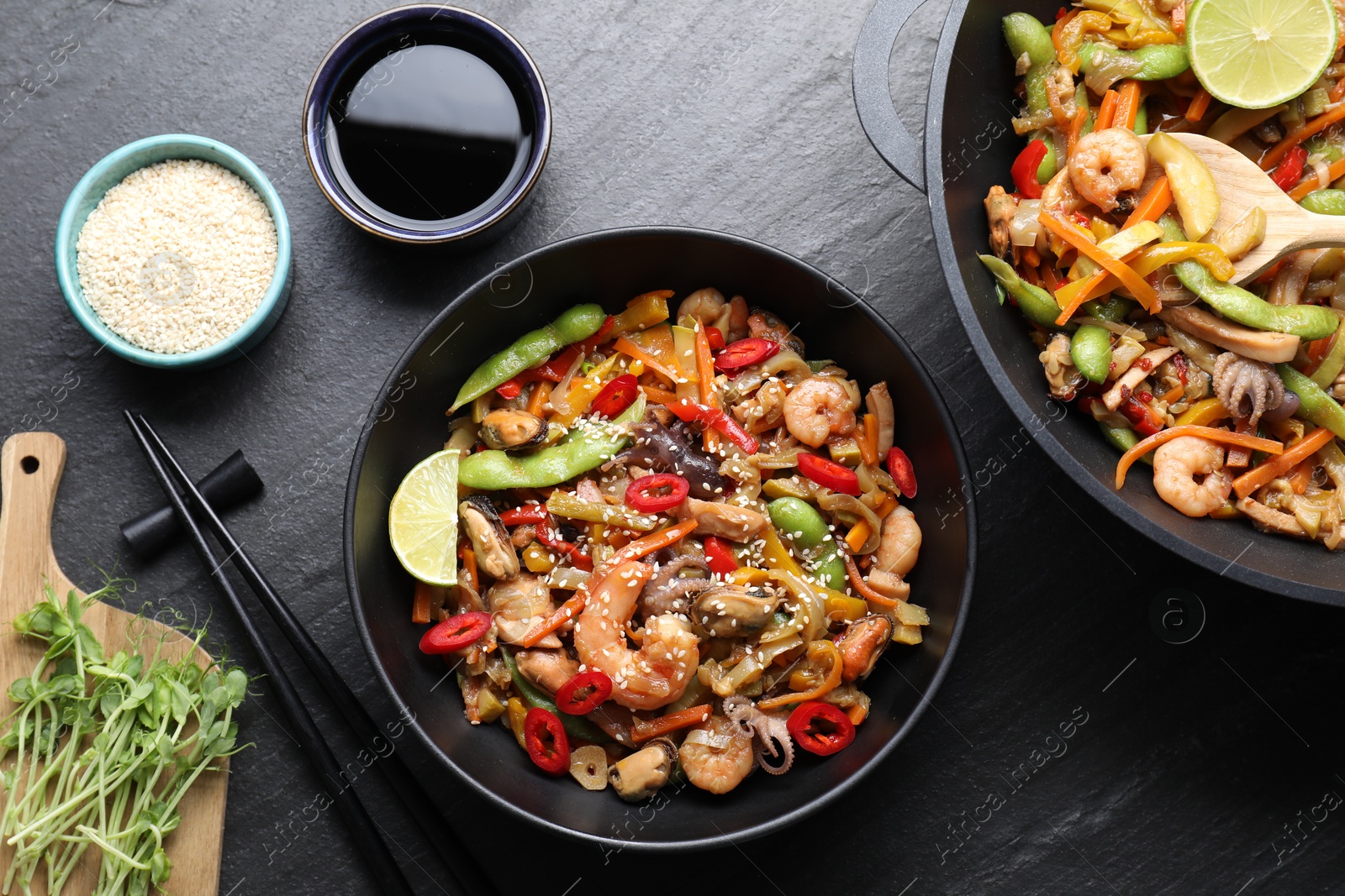 Photo of Stir-fry sea food served on grey textured table, flat lay