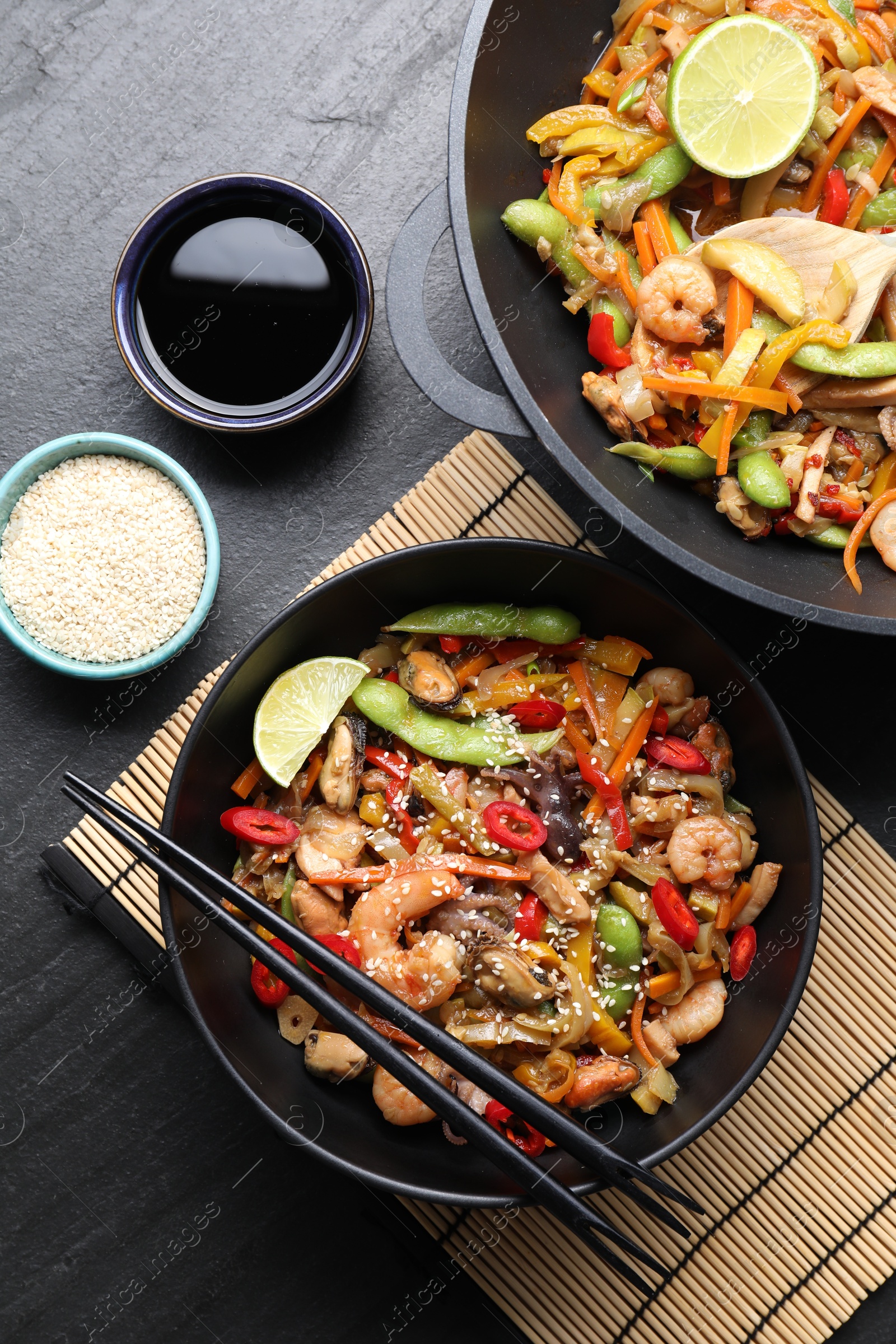 Photo of Stir-fry sea food served on grey textured table, flat lay