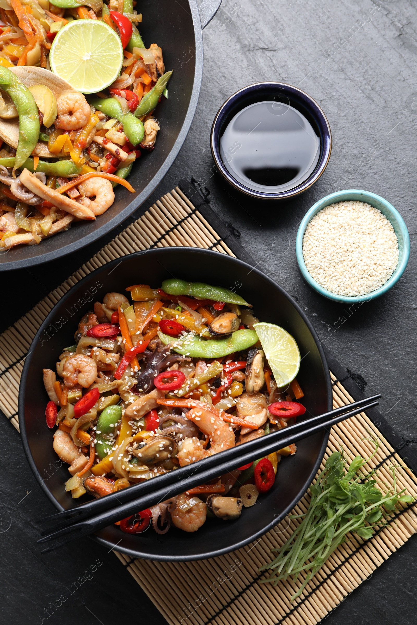 Photo of Stir-fry sea food served on grey textured table, flat lay