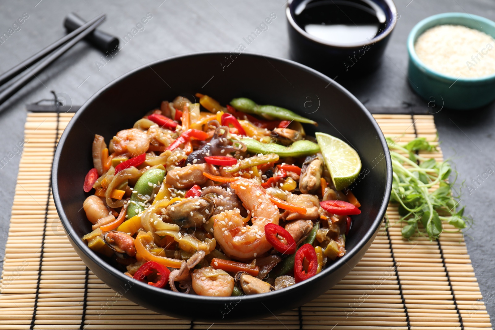 Photo of Stir-fry sea food served on grey table, closeup