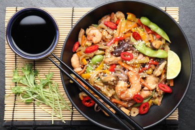 Photo of Stir-fry sea food served on grey textured table, flat lay