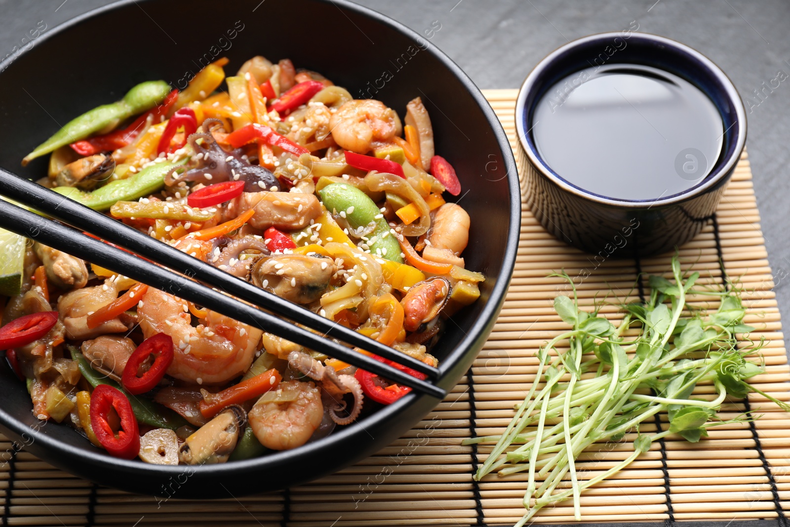 Photo of Stir-fry sea food served on grey table, closeup