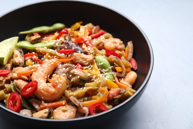 Photo of Stir-fry sea food in bowl on light grey table, closeup