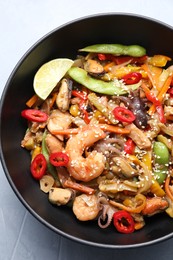 Photo of Stir-fry sea food in bowl on light grey table, top view