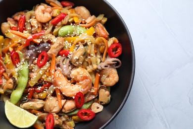 Photo of Stir-fry sea food in bowl on light grey table, top view. Space for text