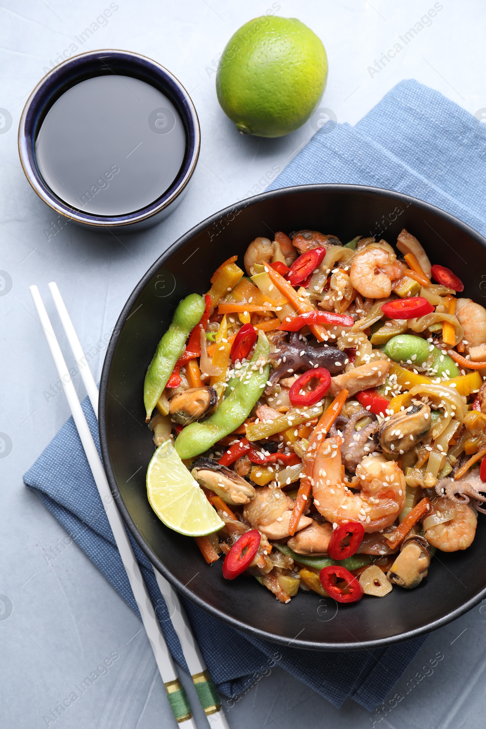 Photo of Stir-fry sea food served on light grey table, flat lay