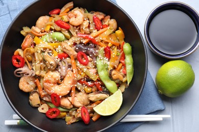 Stir-fry sea food served on light grey table, flat lay