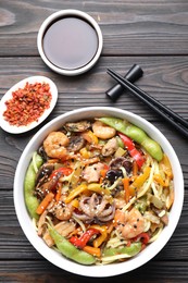 Photo of Stir-fry noodles with sea food served on wooden table, flat lay