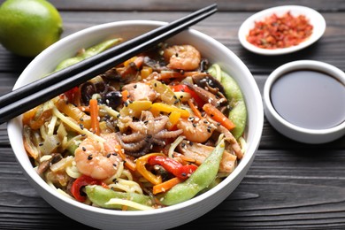 Photo of Stir-fry noodles with sea food served on wooden table, closeup