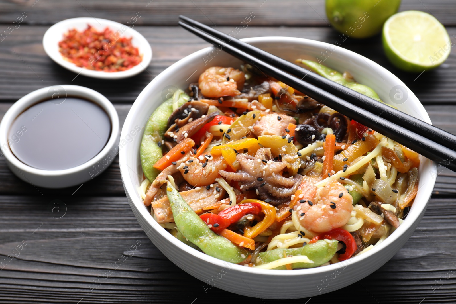 Photo of Stir-fry noodles with sea food served on wooden table, closeup