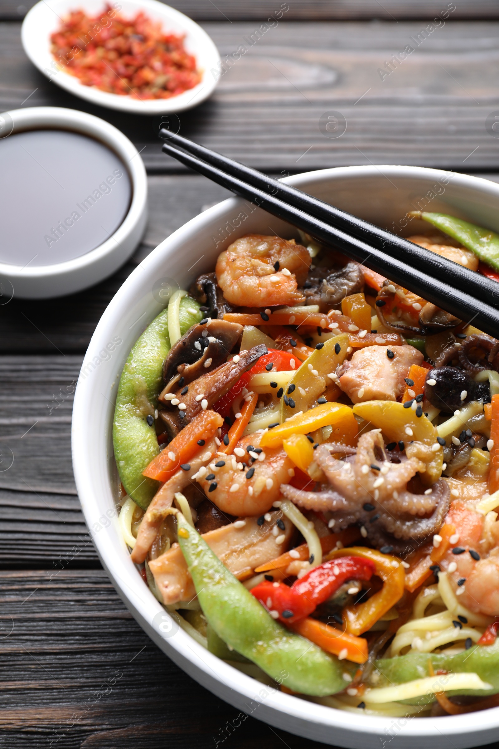 Photo of Stir-fry noodles with sea food served on wooden table, closeup