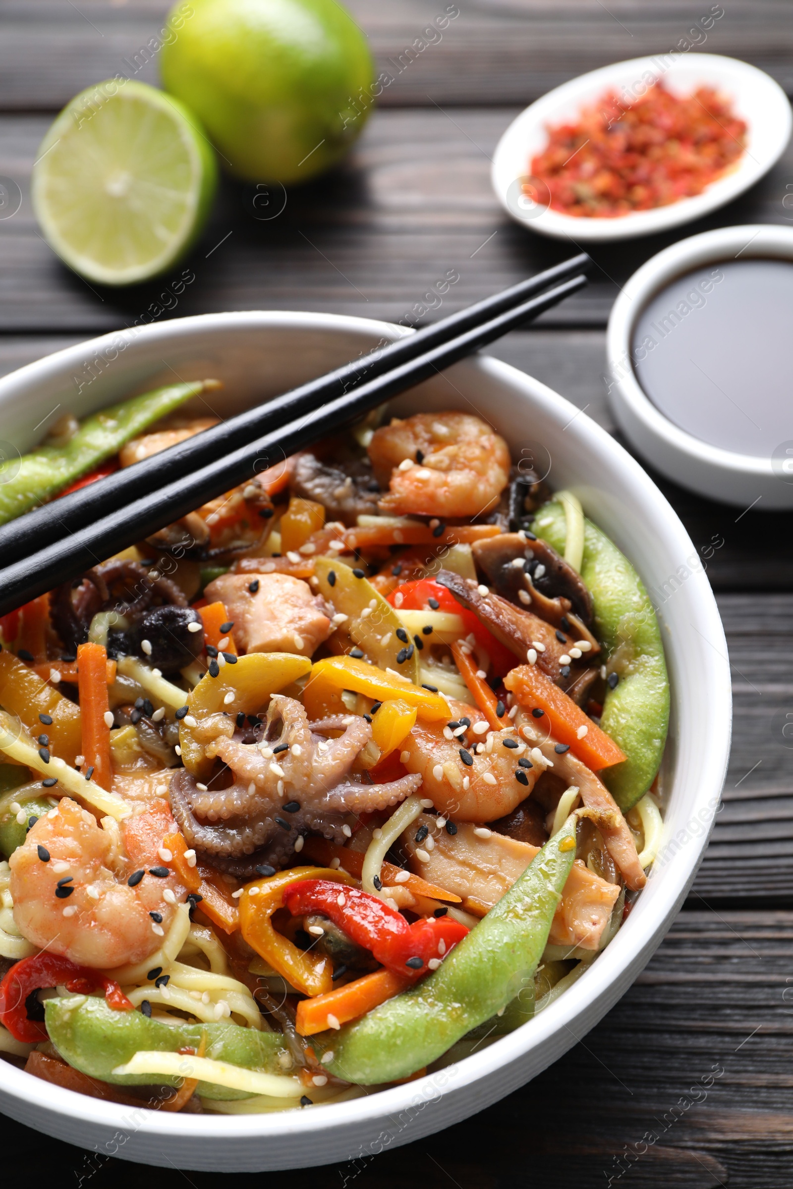 Photo of Stir-fry noodles with sea food served on wooden table, closeup