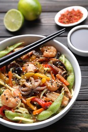 Photo of Stir-fry noodles with sea food served on wooden table, closeup