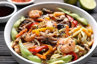 Photo of Stir-fry noodles with sea food in bowl on table, closeup