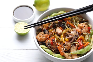 Stir-fry noodles with sea food served on white wooden table, closeup