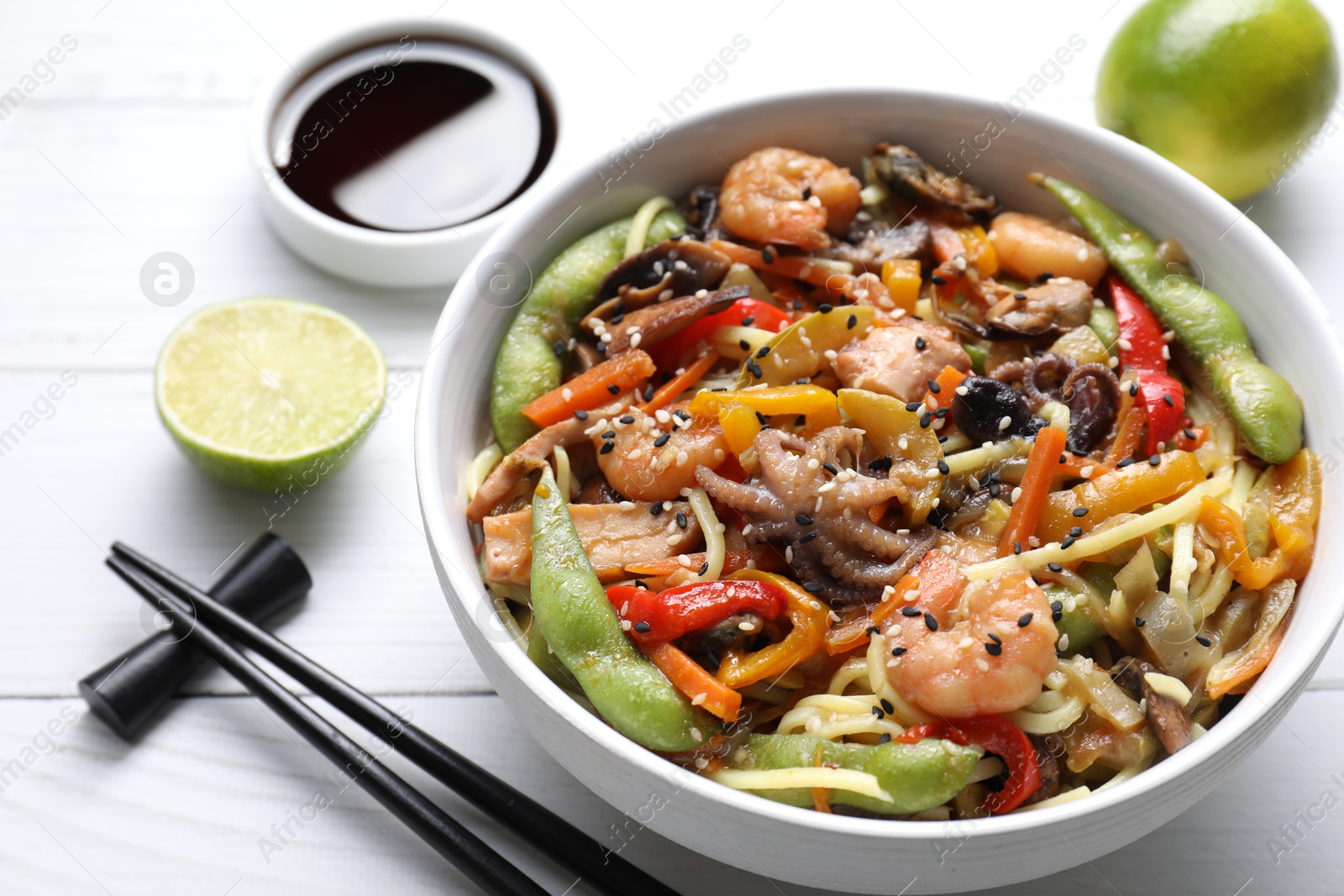 Photo of Stir-fry noodles with sea food served on white wooden table, closeup