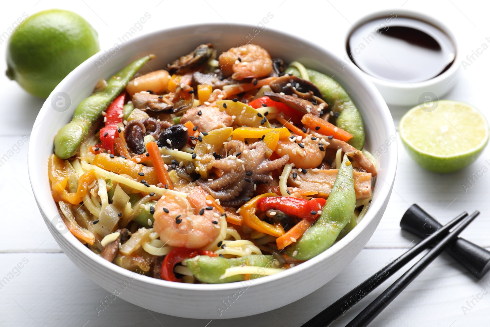 Photo of Stir-fry noodles with sea food served on white wooden table, closeup