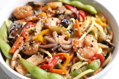 Photo of Stir-fry noodles with sea food in bowl on white table, closeup