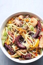 Photo of Stir-fry noodles with sea food in bowl on light grey table, top view