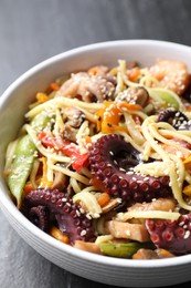 Photo of Stir-fry noodles with sea food in bowl on grey table, closeup