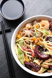 Stir-fry noodles with sea food served on grey textured table, flat lay