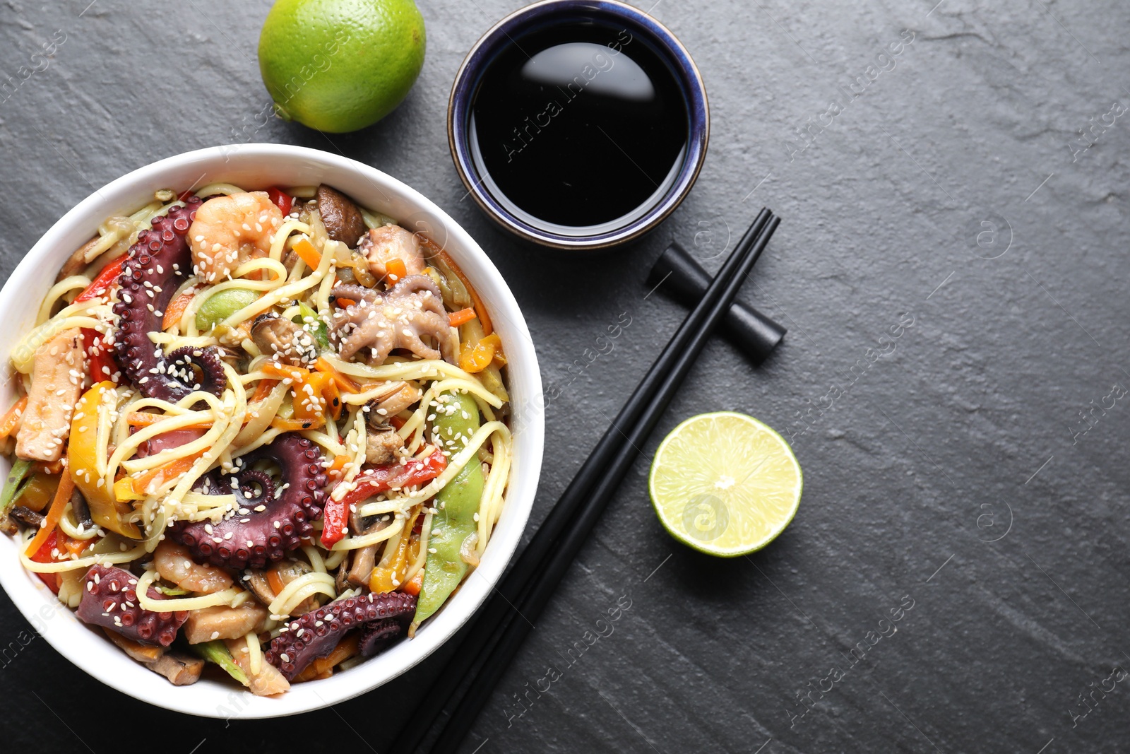 Photo of Stir-fry noodles with sea food served on grey textured table, flat lay