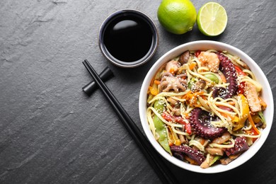 Photo of Stir-fry noodles with sea food served on grey textured table, flat lay