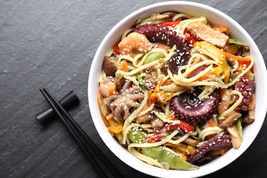 Photo of Stir-fry noodles with sea food served on grey textured table, flat lay