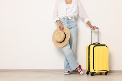 Woman with suitcase and straw hat indoors, closeup. Space for text