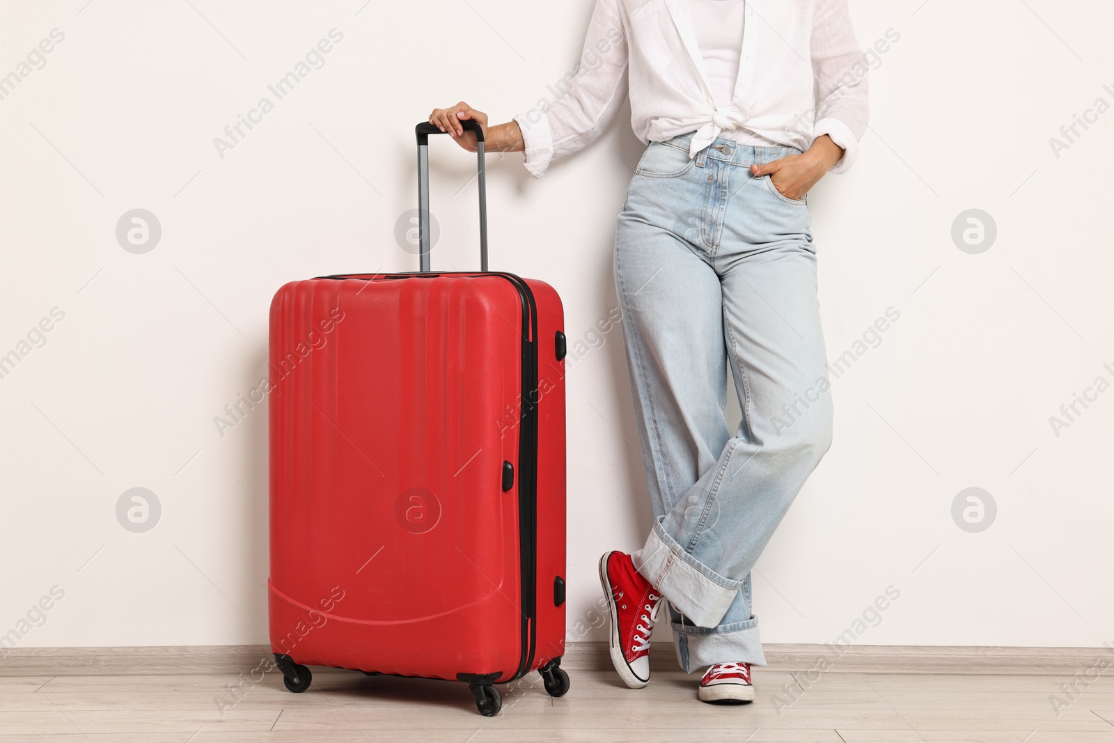 Photo of Woman with red suitcase near light wall indoors, closeup