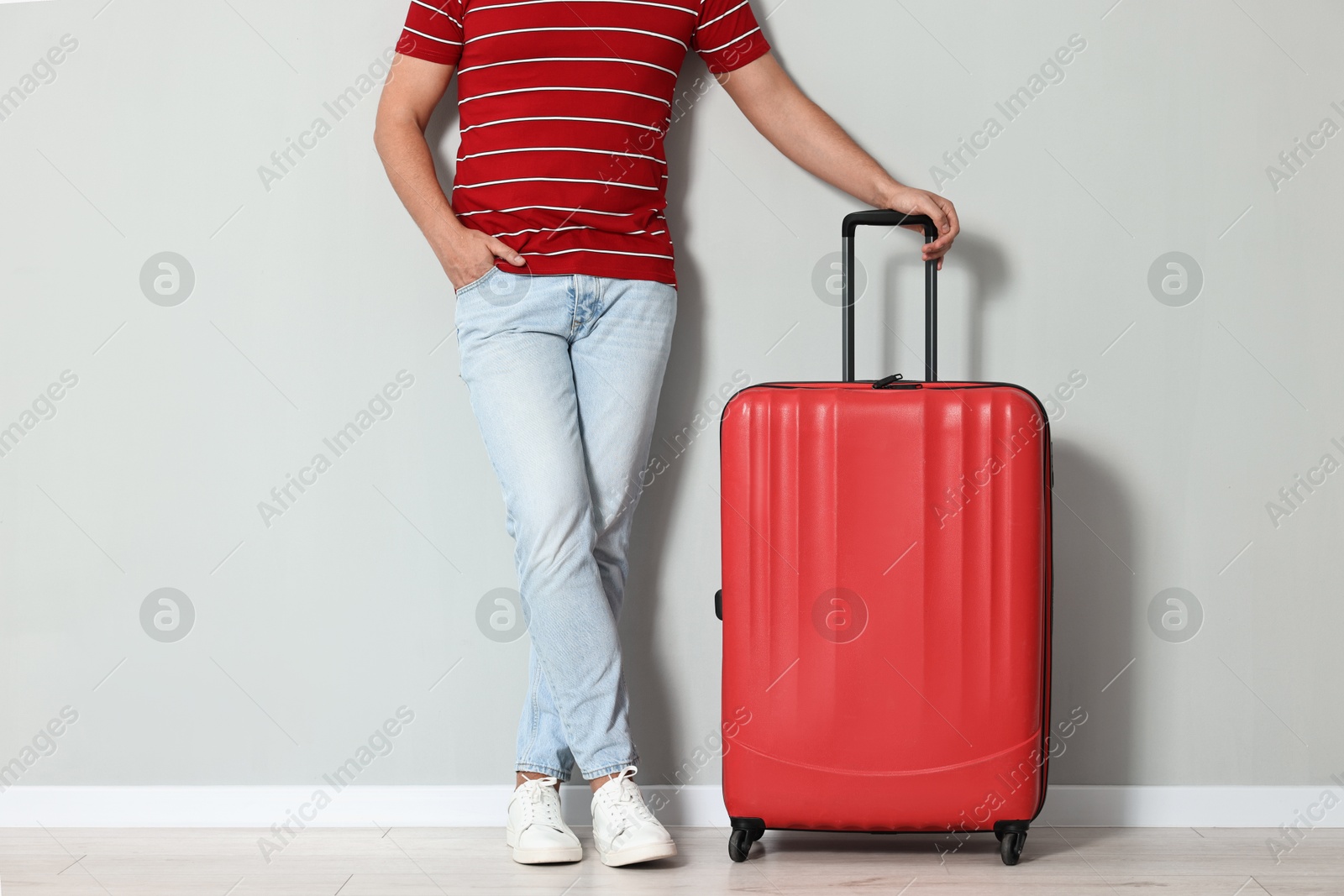 Photo of Man with suitcase near light gray wall indoors, closeup