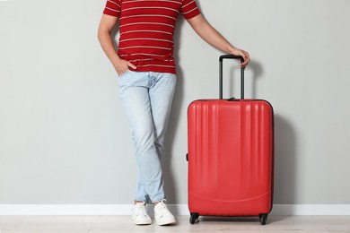 Photo of Man with suitcase near light gray wall indoors, closeup