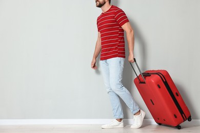 Man with red suitcase walking indoors, closeup