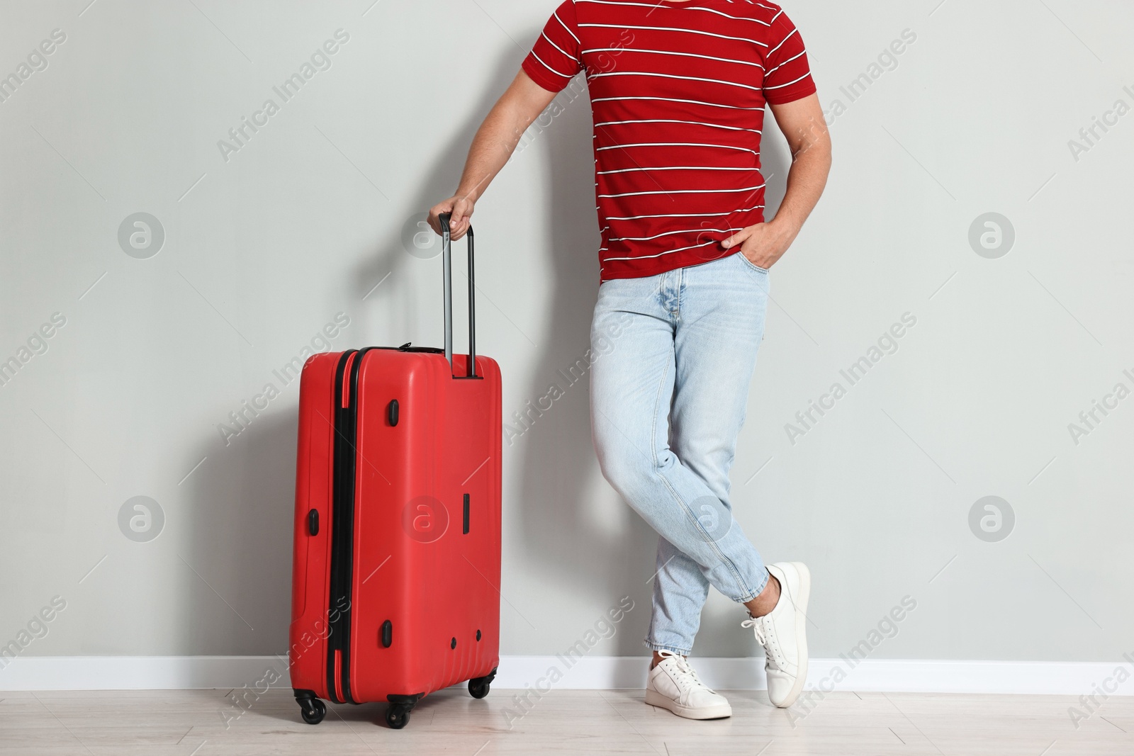 Photo of Man with suitcase near light gray wall indoors, closeup