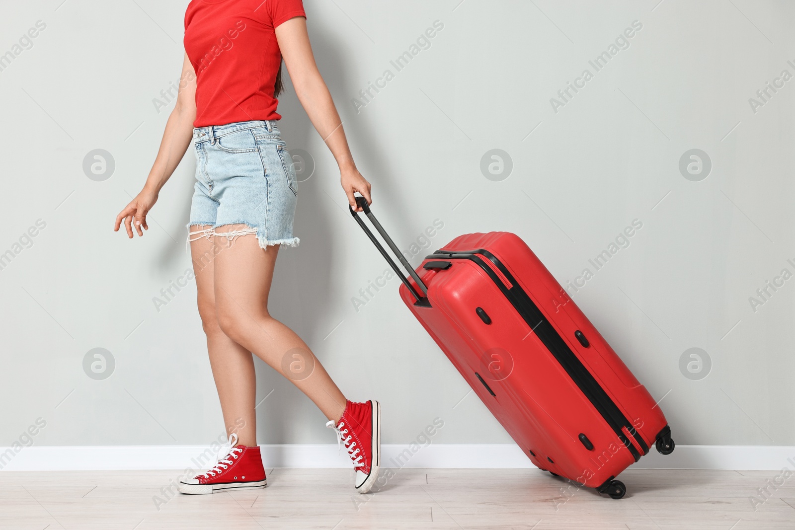 Photo of Woman with red suitcase walking indoors, closeup