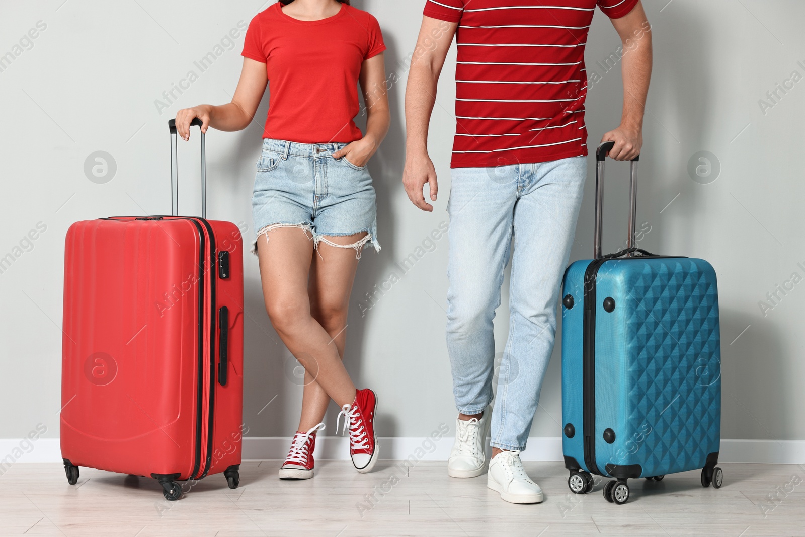 Photo of Man and woman with suitcases near light gray wall indoors, closeup